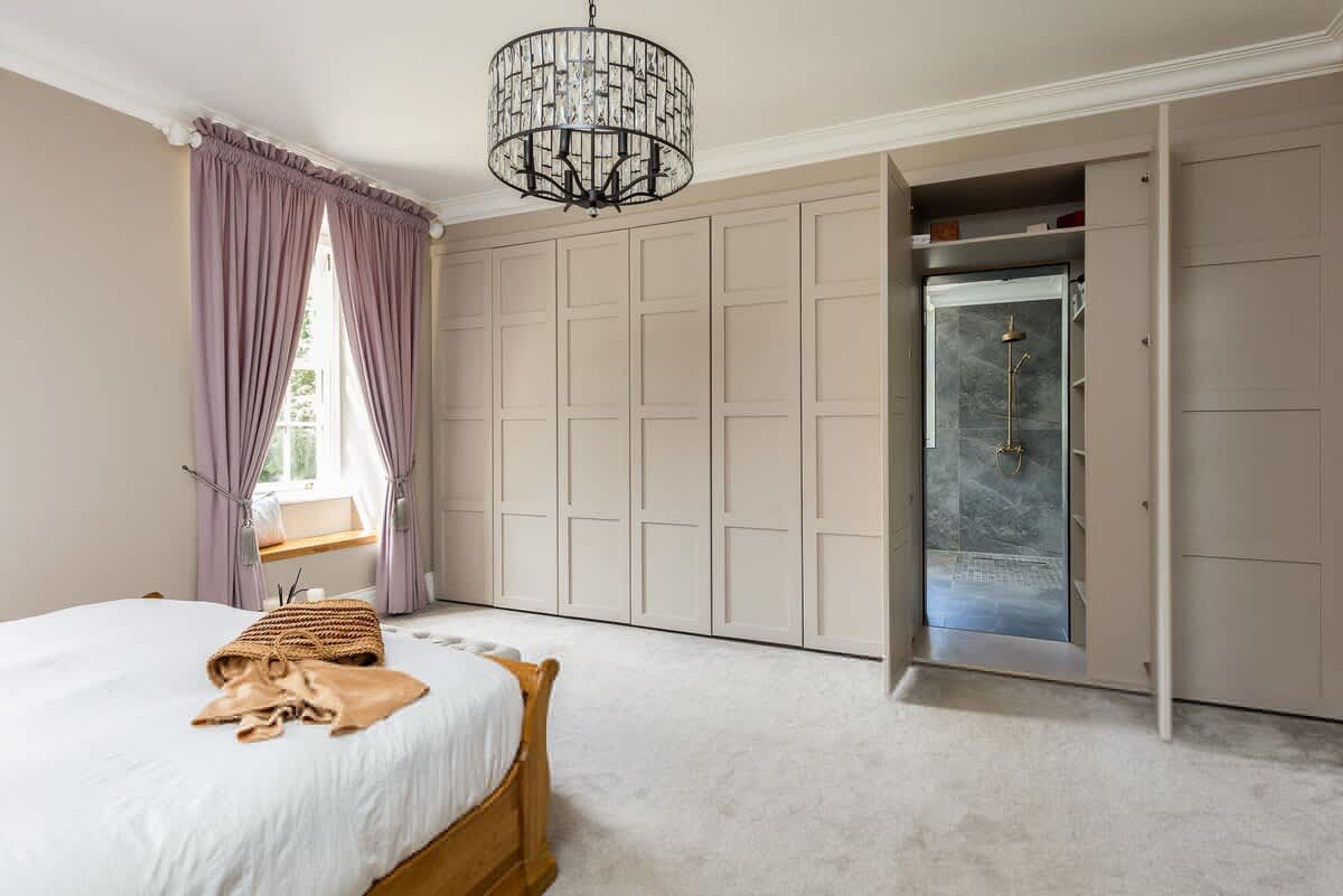 A bedroom with a bed, a wardrobe, and a shower.