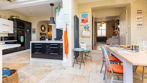 Une cuisine moderne dotée d’un îlot central, d’un coin repas avec des chaises et d’une vue sur le salon.