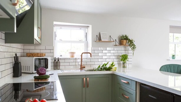 A modern kitchen with white countertops, green cabinets, and a black dishwasher. - Ivy Mews - Converted Barn in Popular Village (Scarborough)