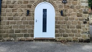 A stone building with a white door and a small window. - Ivy Mews - Converted Barn in Popular Village (Scarborough)