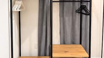 A bunk bed with a wooden frame and two shelves, a hanging light fixture, and a black floor lamp.