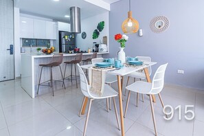 A modern kitchen with white cabinetry, a stainless steel range hood, and a dining area with white chairs and a table set for four. - Luxury I Samaria Private Beach I Swimming Pool I Jacuzzi I spa (Magdalena)