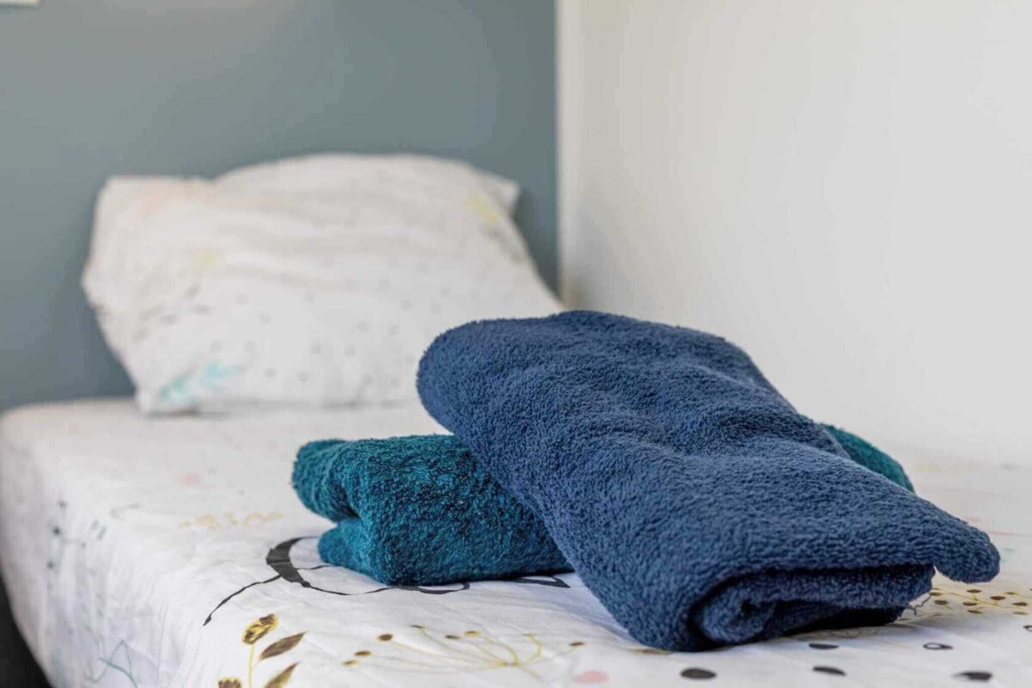 Un letto rifatto con un cuscino bianco e una coperta blu.