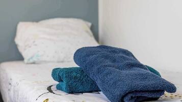 Un letto rifatto con un cuscino bianco e una coperta blu.