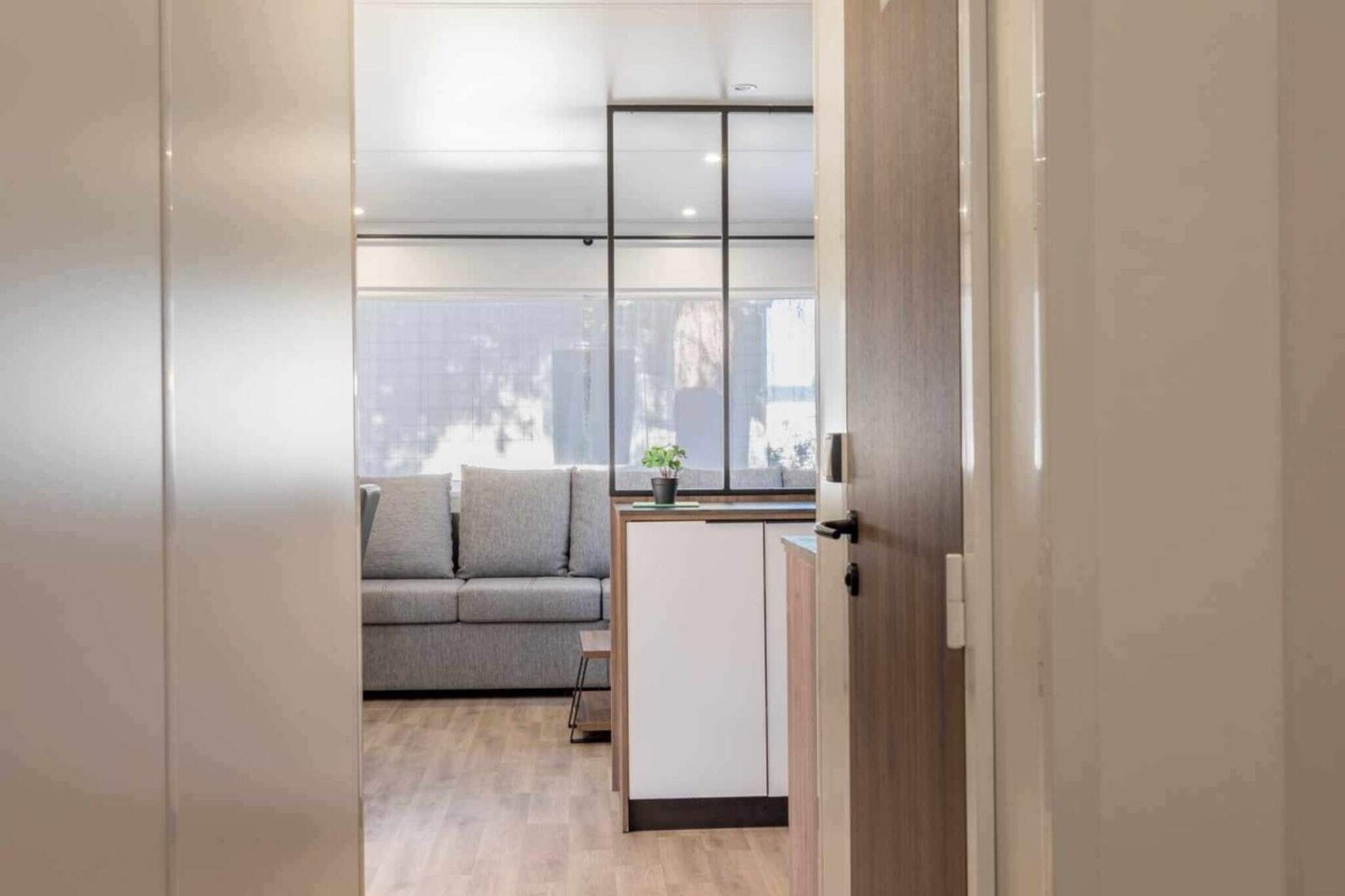 A modern interior with a grey sofa, a small table with a plant, and a white cabinet.