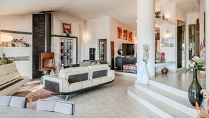 A spacious living area with a piano, a large sofa, and a fireplace. - Magnifique villa avec piscine (Biot)