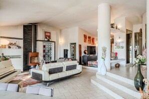 Ein geräumiger Wohnbereich mit einem Klavier, einem großen Sofa und einem Kamin.