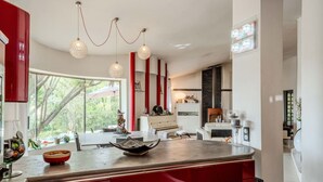 A modern kitchen with a large island, red cabinetry, and pendant lighting. - Magnifique villa avec piscine (Biot)