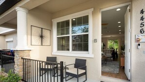 A covered outdoor seating area with wicker chairs and a black metal railing. - Renovated 4BR Townhome w/ Disney Game Room (Kissimmee)