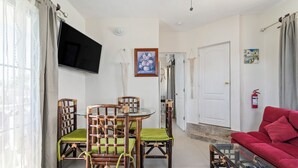 Ein Wohnzimmer mit einem roten Sofa, einem Glastisch und einem Essbereich mit Holzkästen und einem Glastisch.