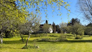 A white building with a red roof, surrounded by green grass and trees.