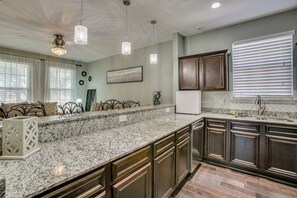 Eine Küche mit Granitarbeitsplatten, Holzschränken, Pendelleuchten und einem eingebauten Kühlschrank.