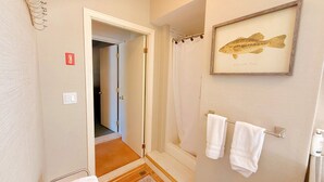 A bathroom with a shower, a framed fish picture, and two towels hanging on a rack. - Lakeview, pet friendly apartment with lake access (Greenville)