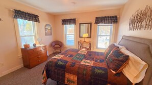 A bedroom with a bed, dresser, chair, lamp, and windows. - Lakeview, pet friendly apartment with lake access (Greenville)