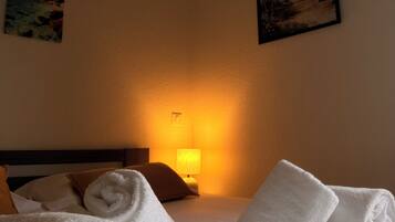 Habitación de hotel con una cama bien hecha, una lámpara y dos cuadros en las paredes.