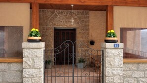 A stone entrance with a metal gate, potted plants, and a number plaque. - Casa Stella  (Olmeto)
