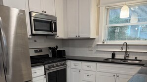 Een moderne keuken met witte kasten, roestvrijstalen apparatuur en een betegelde vloer.