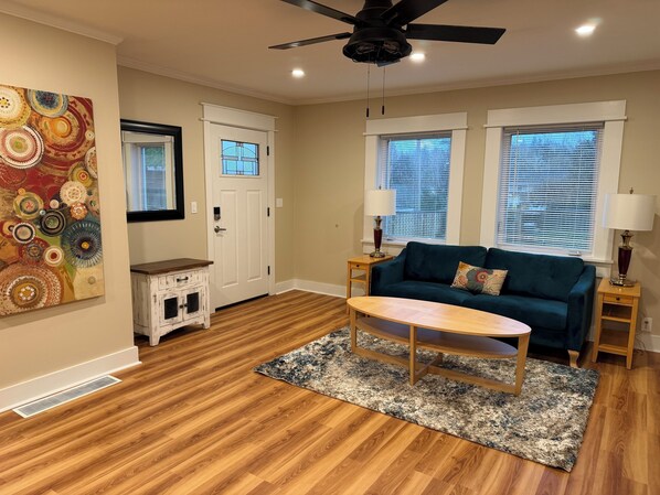 A living room with a blue sofa, a wooden coffee table, and a patterned rug. - Enjoyable 2-bedroom house in Tukwila perfect for your getaway (Tukwila)