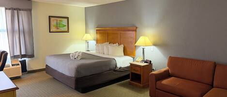 A hotel room with a bed, two bedside lamps, a wooden nightstand, a chair, and a desk.