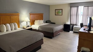 Une chambre d’hôtel avec deux lits, un bureau équipé d’un ordinateur, un téléphone et une poubelle.