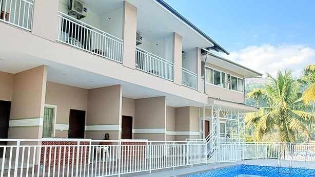Un hotel con piscina, varios balcones y un cielo azul despejado.