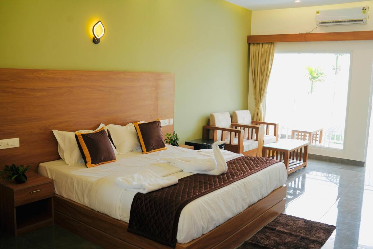 A hotel room with a wooden bed, a bedside table, a small desk, and a chair.