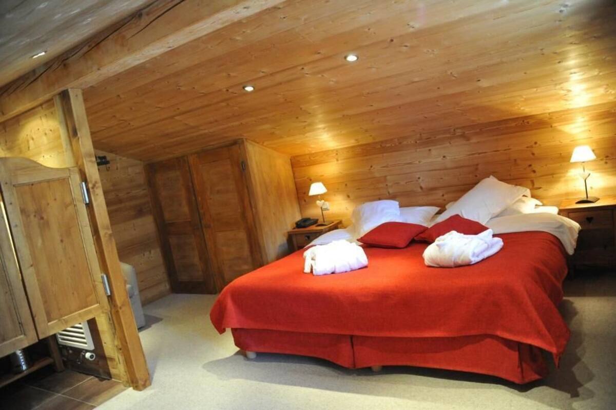 Una stanza con rivestimenti in legno, un letto, due comodini e un tavolino da notte.