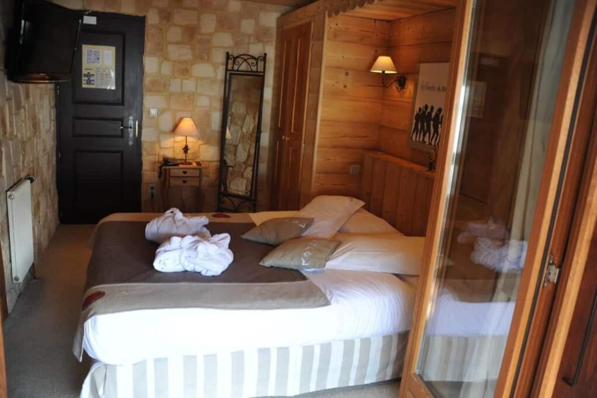 Una stanza in legno con un letto, uno specchio, un comodino e una lampada.