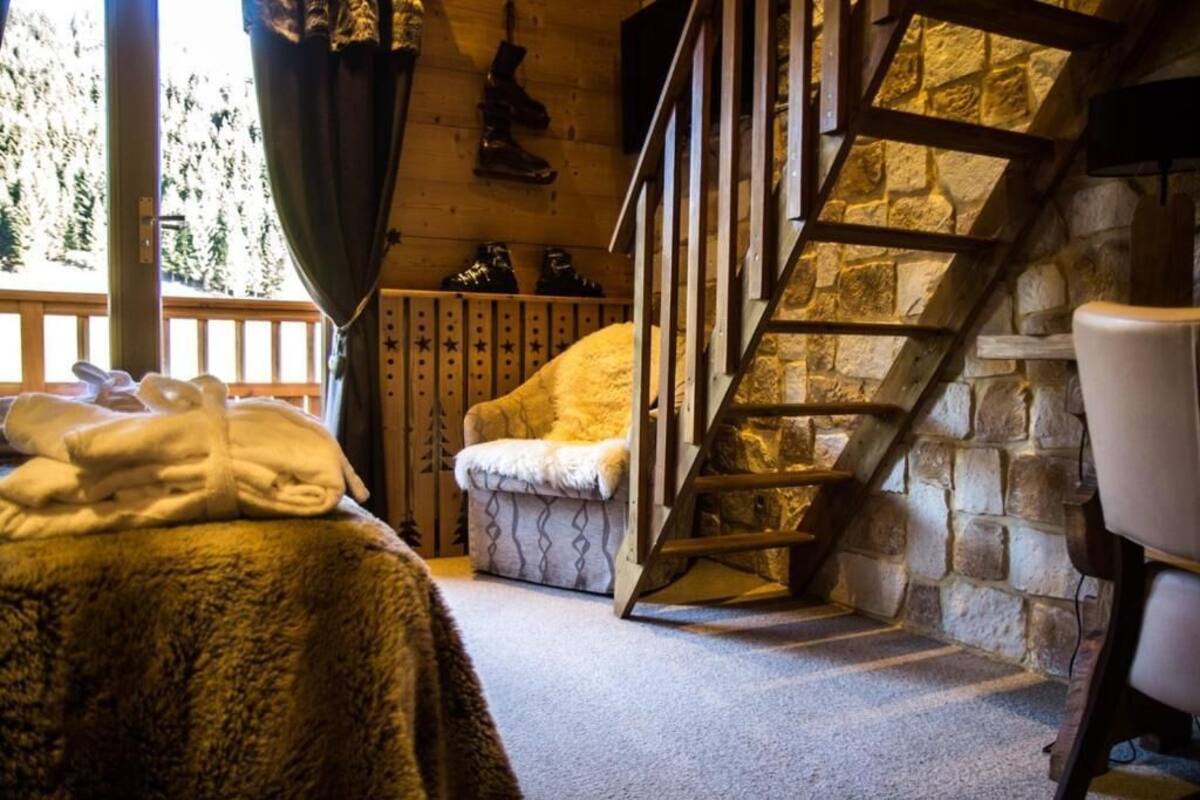 Una camera accogliente con una scala in pietra, una poltrona confortevole e un letto con asciugamani.