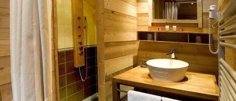 Une salle de bain rustique, aménagée dans une cabane en bois, avec une douche, un lavabo et un porte-serviettes.