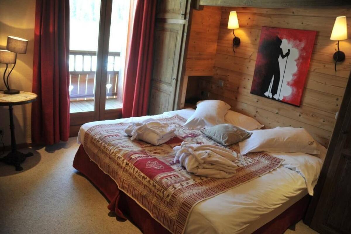 Un letto rifatto con cuscini e coperte, un tavolino con una lampada e un quadro appeso al muro.