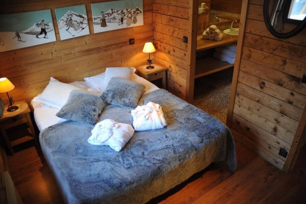 Una camera accogliente in legno con un letto, un comodino, uno specchio e opere d'arte alle pareti.