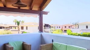 Ein überdachter Patio-Bereich mit zwei Korbschaukeln und einem Deckenventilator.