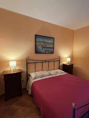 A bedroom with a bed, two bedside tables with lamps, a painting on the wall, and a tiled floor. - Lots of comforts near the sea, Cefalù, with the possibility of using the pool (Contrada Pistavecchia 1)