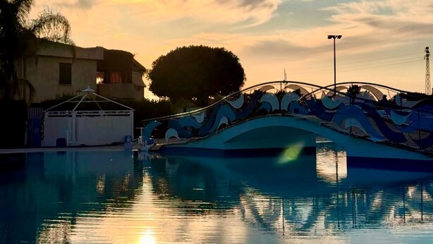 Ein Boot liegt an einem Pool, im Hintergrund ein Sonnenuntergang.