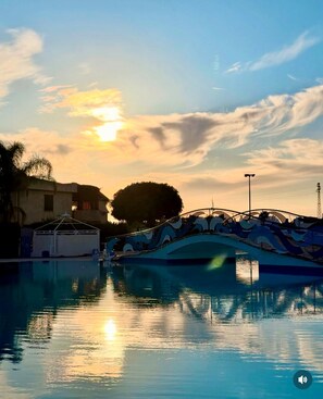 A boat docked at a swimming pool with a sunset in the background. - Lots of comforts near the sea, Cefalù, with the possibility of using the pool (Contrada Pistavecchia 1)