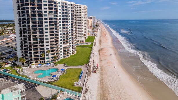 Un hotel moderno con numerosi balconi, posizione fronte spiaggia e area piscina.