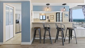 Una cucina con angolo bar, mobili bianchi e vista sull'oceano.