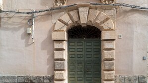 Fachada de edificio con puerta verde, pared de piedra y el número 116.