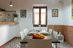 Ein Essbereich mit Tisch für vier Personen, einem Blumentopf und Bildern an den Wänden.