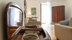 Una habitación con un tocadiscos antiguo, un sofá, una silla y un aparador de madera.