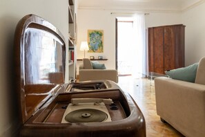 Ein Zimmer mit einem Vintage-Plattenspieler, einer Couch, einem Sessel und einem Holzschrank.
