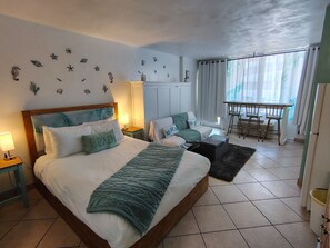 A bedroom with a bed, bedside tables, a desk, and a chair. - Ocean Front Studio (Daytona Beach)