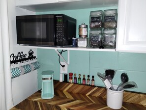A kitchen with a microwave, coffee maker, and various coffee and tea containers. - Ocean Front Studio (Daytona Beach)