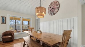 Et spiseområde med et træbord, bænke og en pendellampe i fletværk.