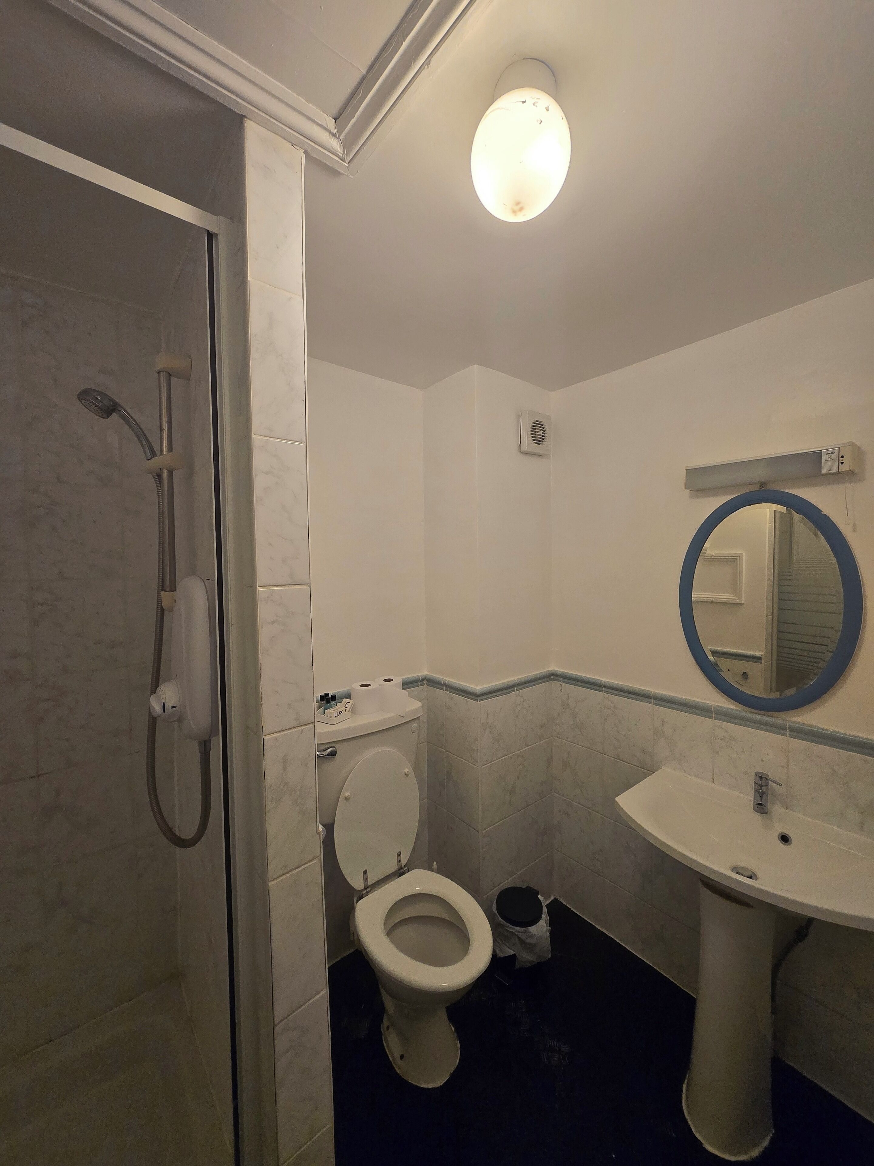 Un baño con ducha, inodoro, lavabo y espejo.