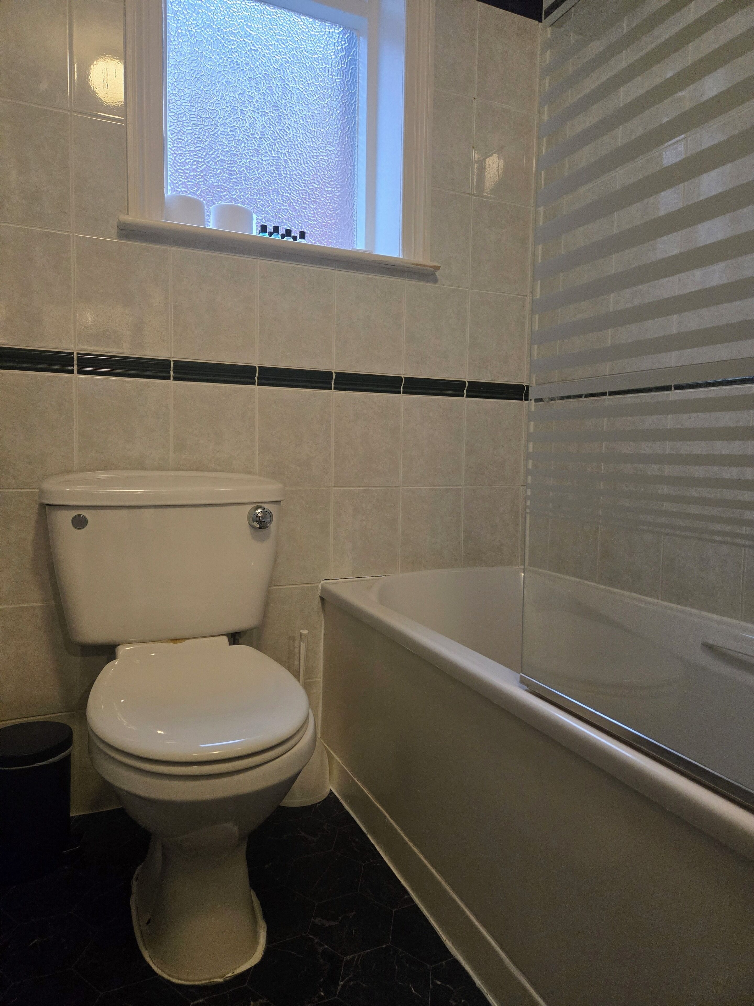 A bathroom with a toilet, a bathtub, and a window.