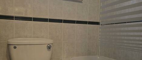 Un baño con inodoro, bañera y ventana.