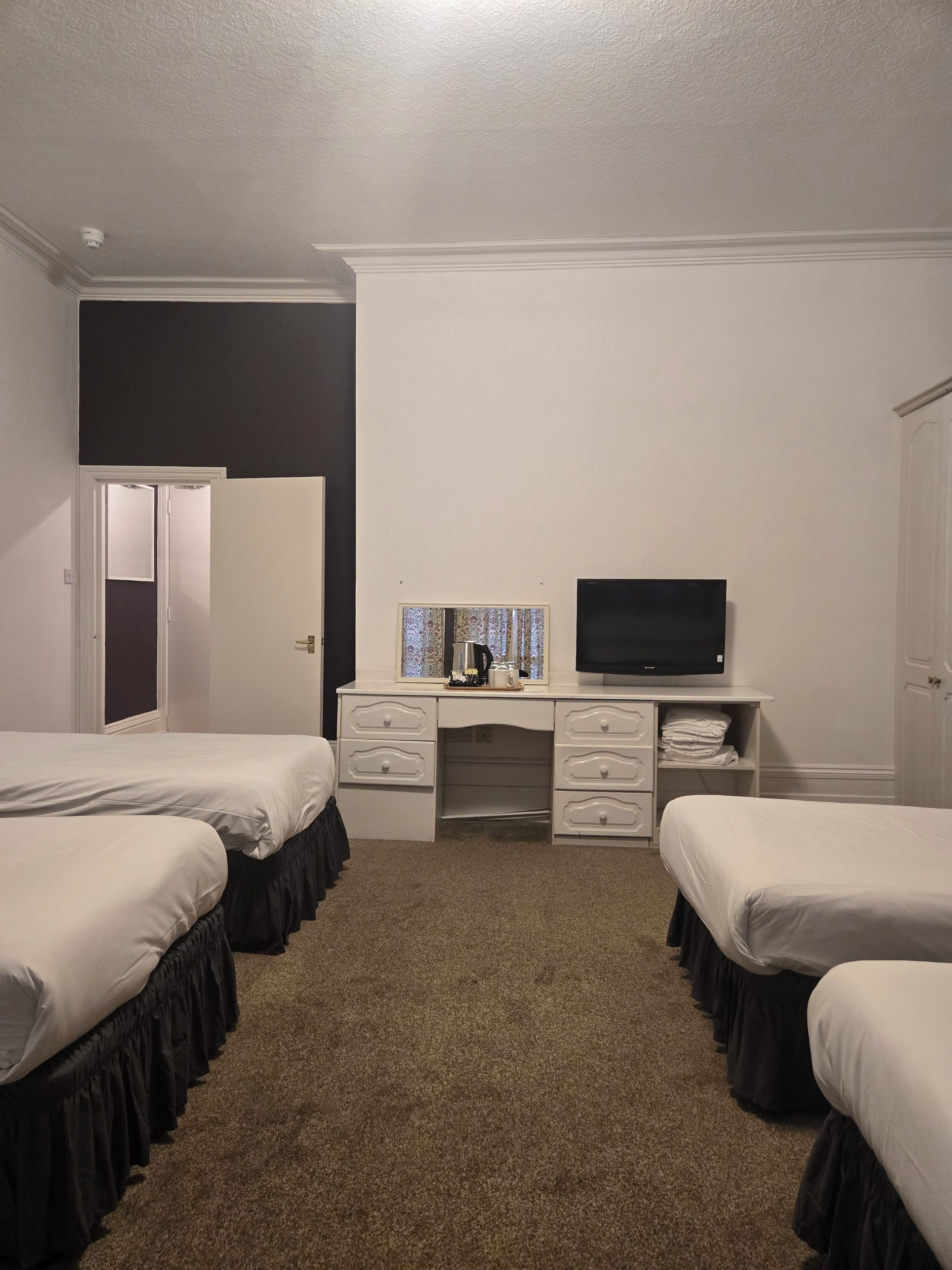 A hotel room with two beds, a desk with a television, and a window with a view.