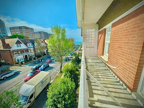 A balcony with a view of a street, a parked truck, and a building with a red brick facade. - Hotel Langfords Brighton (Hove)